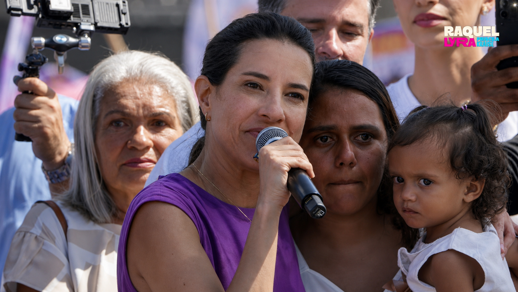 Raquel Lyra fala ao microfone cercada de apoiadoras e uma criança de colo