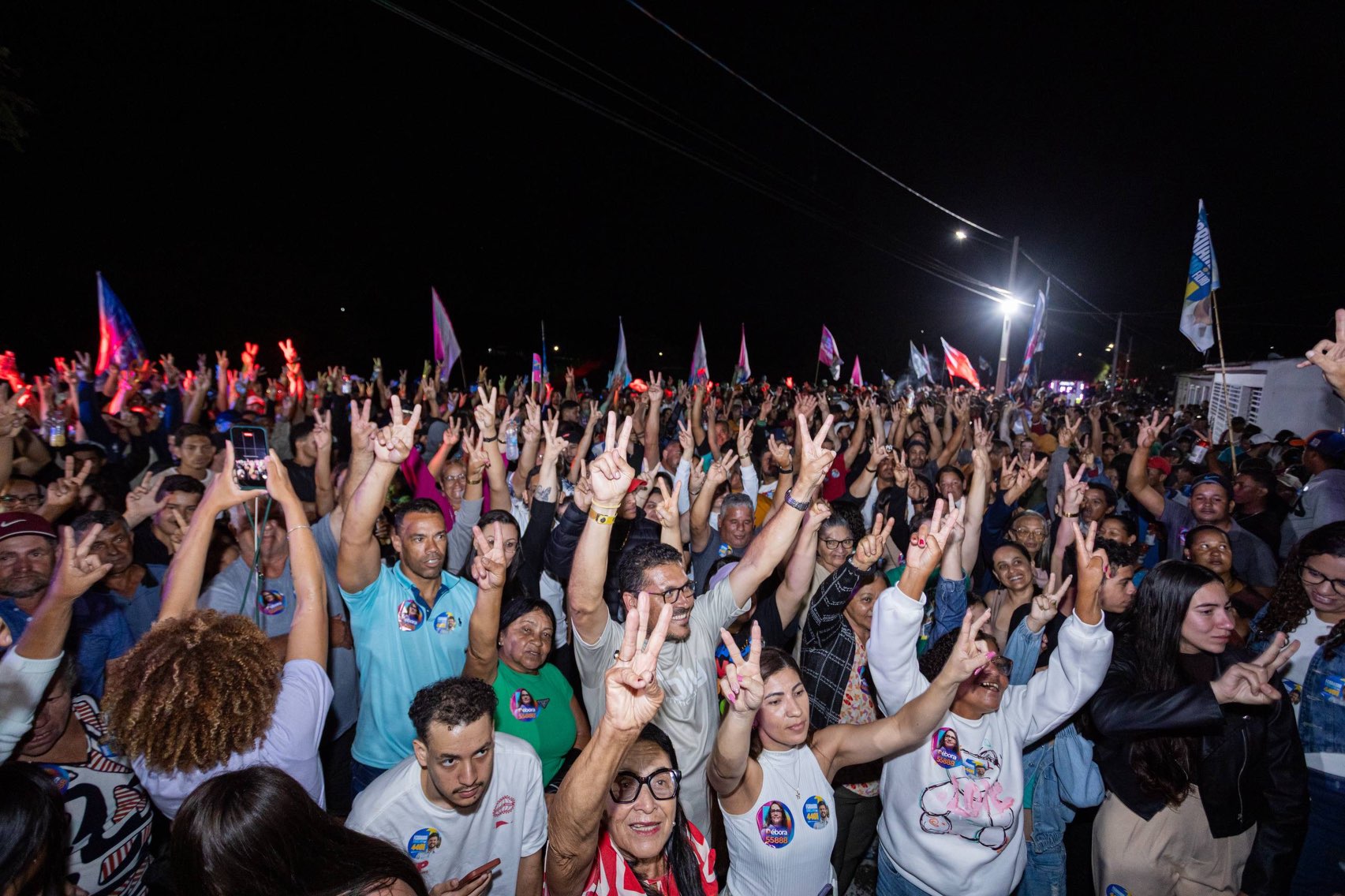 Pessoas reunidas no encontro erguem os braços diante do palco